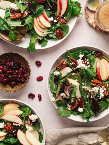 bowls of salad with mixed greens and apples and pecans